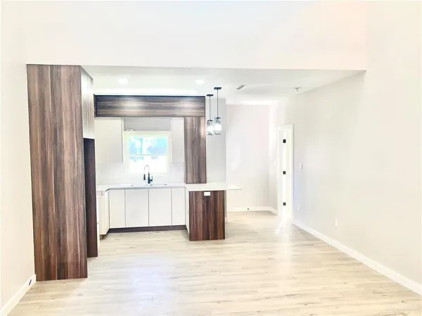 a large white kitchen with a sink and dishwasher a refrigerator with wooden floor