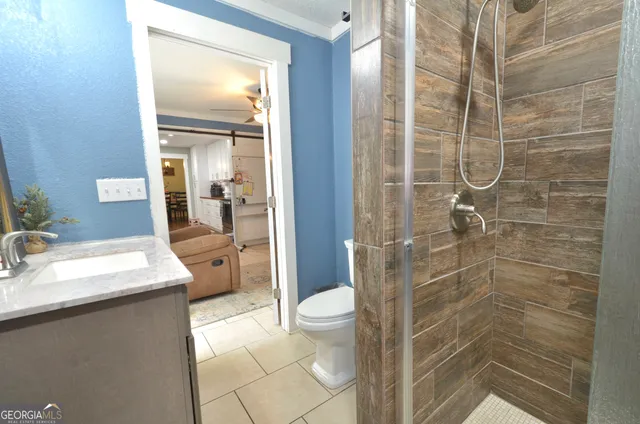 a bathroom with a granite countertop sink a toilet and shower