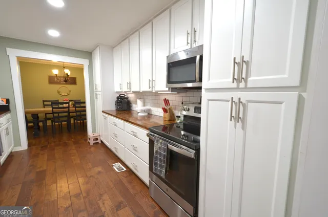 a kitchen with stainless steel appliances white cabinets and wooden floor