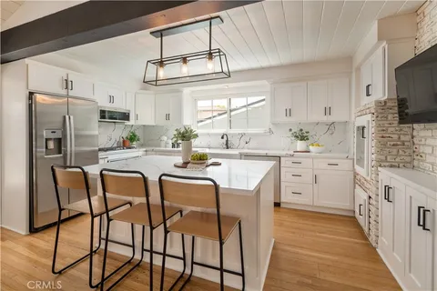 a kitchen with stainless steel appliances kitchen island granite countertop a refrigerator a stove a microwave oven a sink with island and chairs