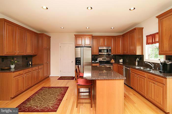 4830 Roop Road Mount Airy, MD 21771 - Photo 9 of 30 a kitchen with stainless steel appliances granite countertop a stove top oven a sink dishwasher a refrigerator and cabinets with wooden floor