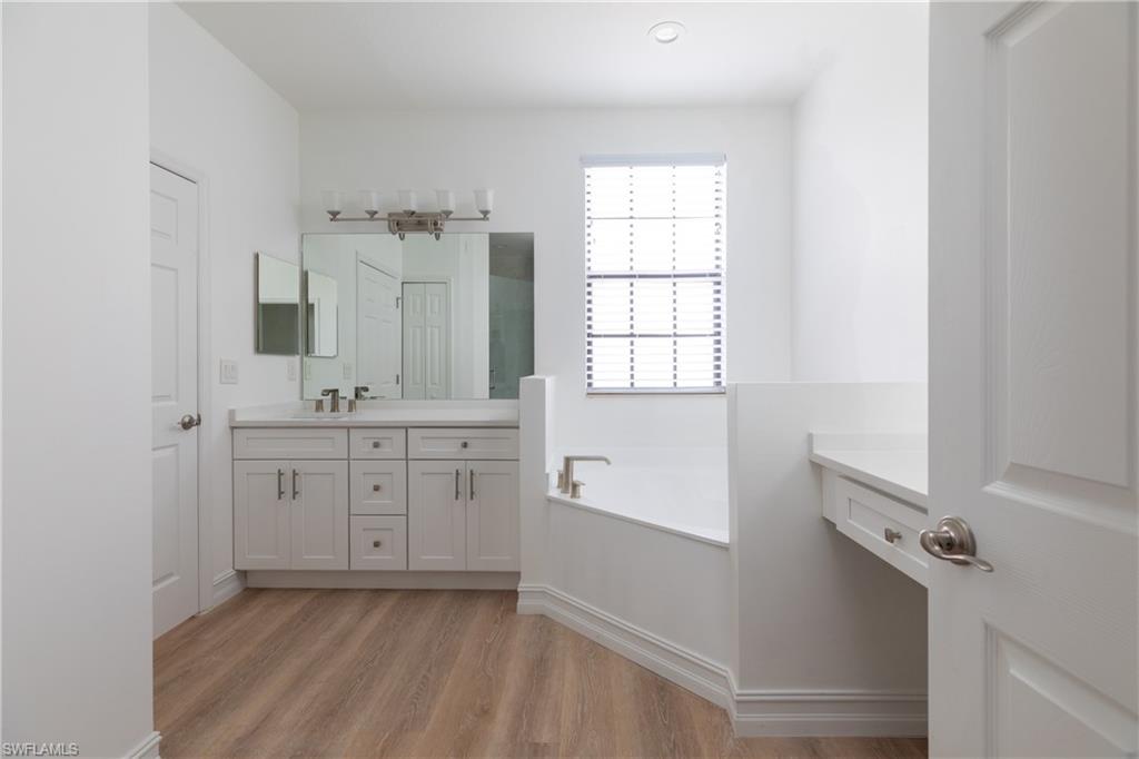 15618 Summit Pl Circle, Unit 396 Naples, FL 34119 - Photo 21 of 41 a spacious bathroom with a double vanity sink a mirror and a bathtub
