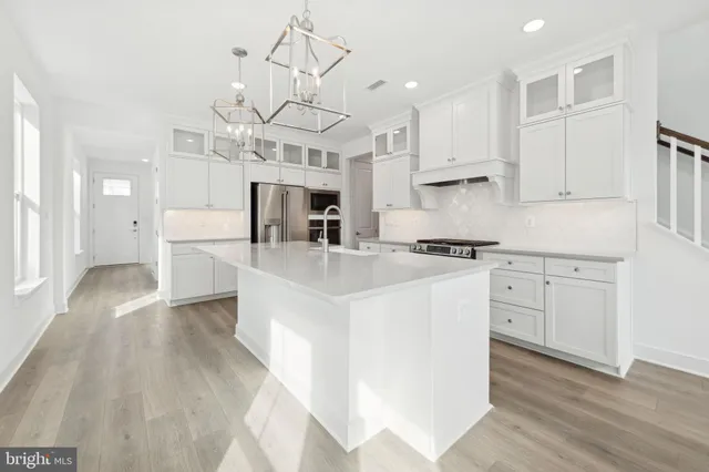 a kitchen with stainless steel appliances kitchen island hardwood floor sink and cabinets
