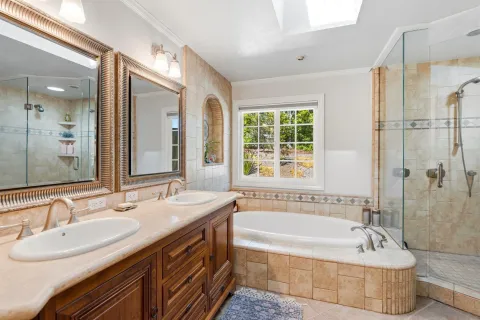 a bathroom with a granite countertop tub sink and mirror