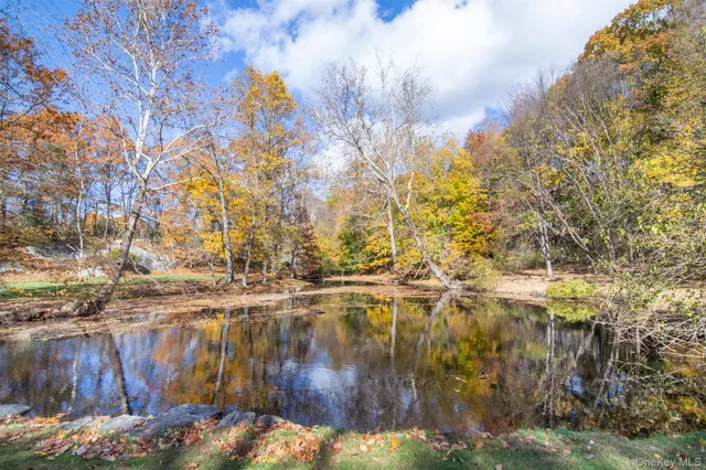 a view of a brick house next to a yard with large trees