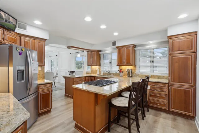 a kitchen with granite countertop a refrigerator stove top oven dining table and chairs
