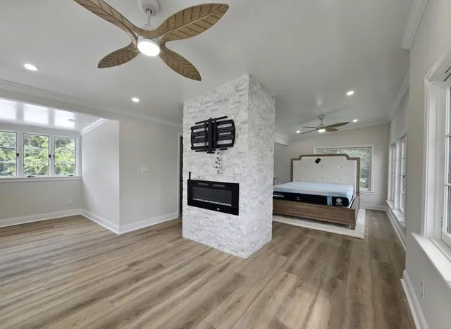 an empty room with wooden floor fireplace and windows