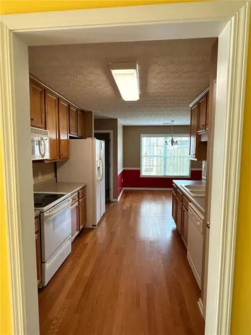 a kitchen with a refrigerator a sink and wooden floor