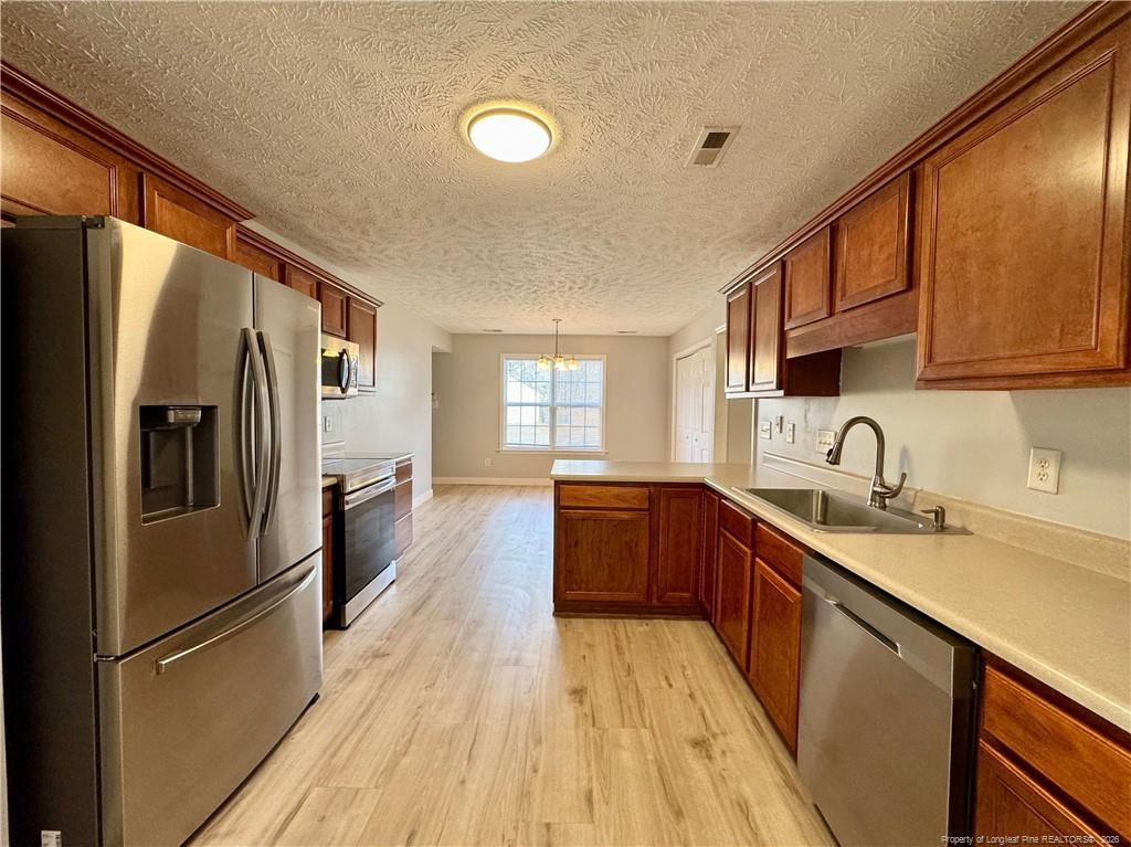 5503 Rising Ridge Drive Hope Mills, NC 28348 - Photo 5 of 18 a kitchen with stainless steel appliances granite countertop a refrigerator sink and wooden cabinets