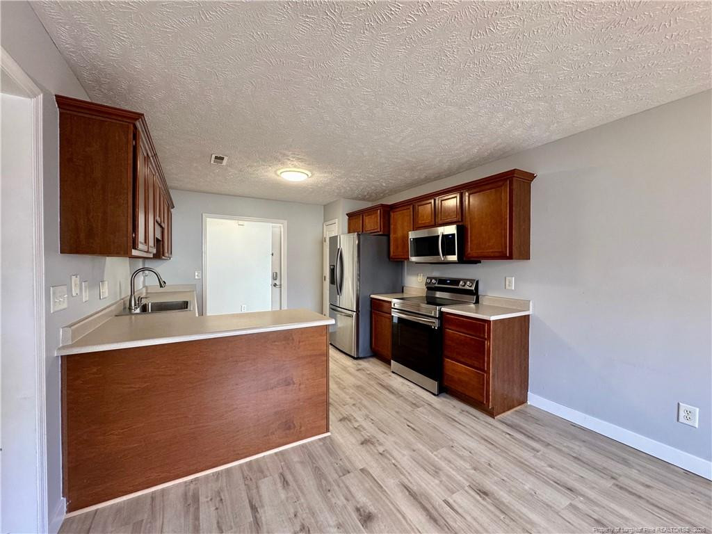5503 Rising Ridge Drive Hope Mills, NC 28348 - Photo 6 of 18 a large kitchen with stainless steel appliances a large counter top a stove a sink and a refrigerator