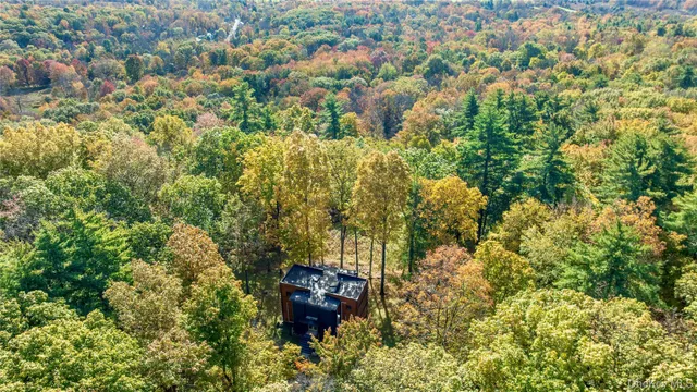 an aerial view of residential house with outdoor space and trees all around