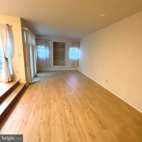 a view of a big room with wooden floor and windows