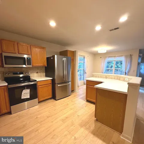 a kitchen with stainless steel appliances granite countertop a refrigerator a sink a stove a microwave and island