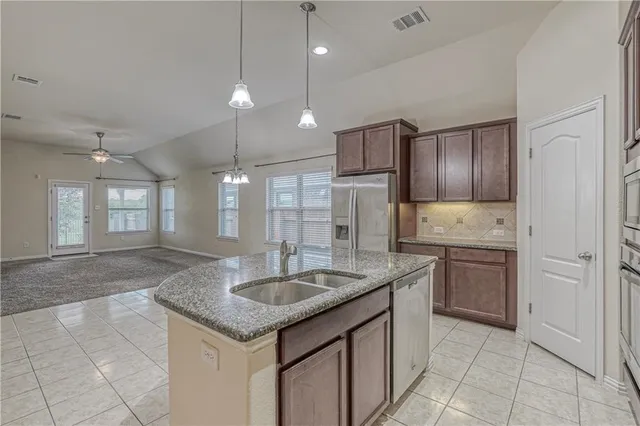 a kitchen with kitchen island granite countertop a sink a counter space appliances and cabinets
