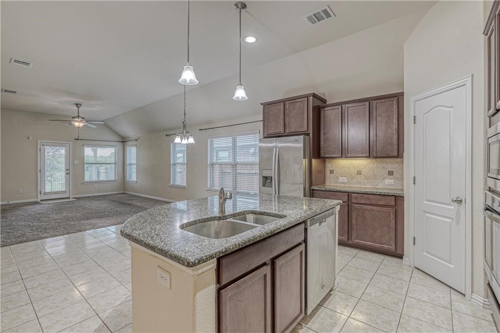 3517 Grail Hollows Road Pflugerville, TX 78660 - Photo 28 of 40 a kitchen with kitchen island granite countertop a sink a counter space appliances and cabinets