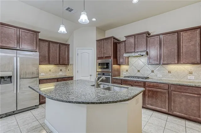 a kitchen with kitchen island granite countertop a sink stove and refrigerator