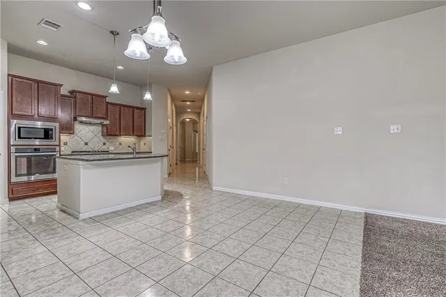 a kitchen with kitchen island granite countertop stainless steel appliances cabinets a sink and a counter top