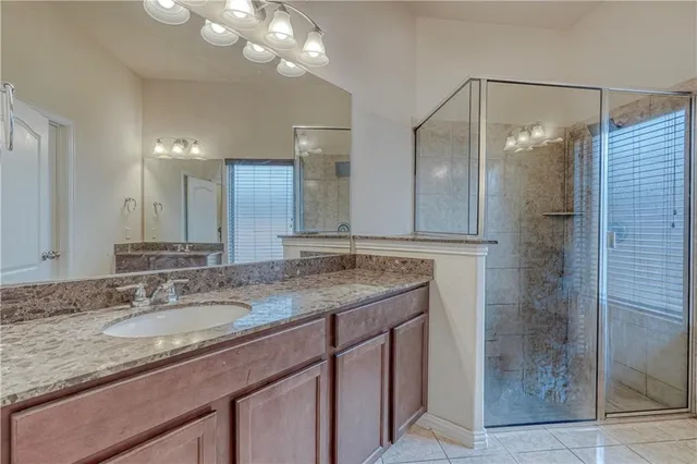 a bathroom with a granite countertop sink a mirror and shower