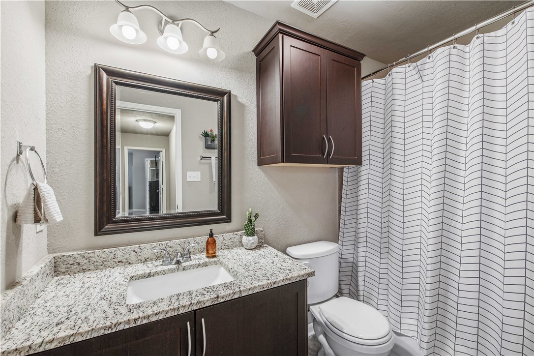 3014 Positano Loop Bryan, TX 77808 - Photo 18 of 23 a bathroom with a granite countertop sink toilet and mirror