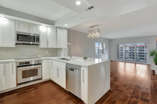 a kitchen with stainless steel appliances granite countertop white cabinets granite counter tops and a wooden floors