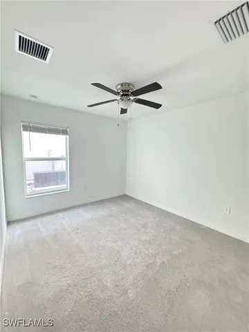 an empty room with a ceiling fan and a window