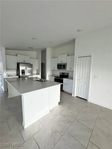 a large kitchen with kitchen island granite countertop a stove a sink a counter top space and cabinets