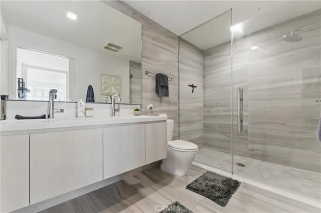 a bath room with a toilet a sink and a mirror