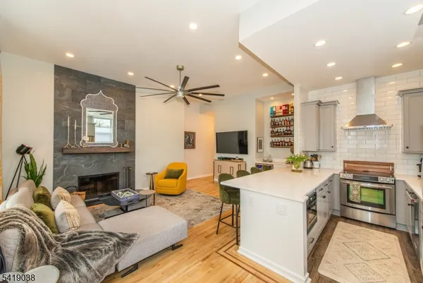 a living room with stainless steel appliances furniture a flat screen tv and kitchen view