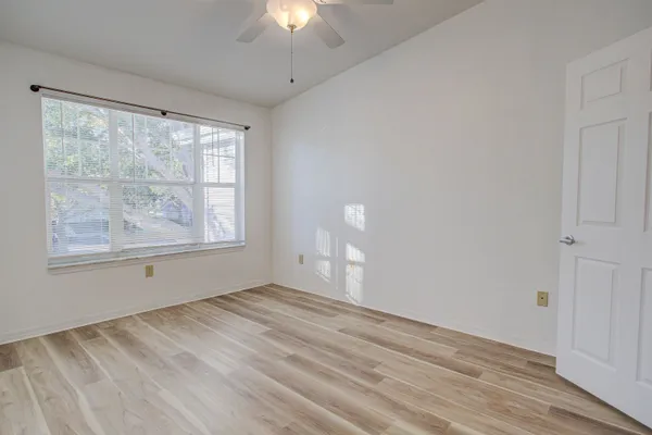 a view of empty room with wooden floor and fan