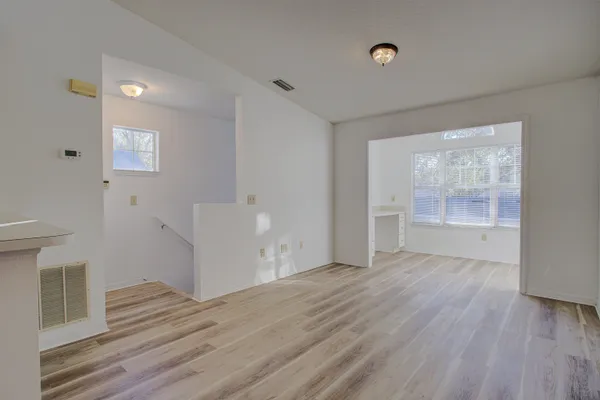 a view of an empty room with wooden floor and a window