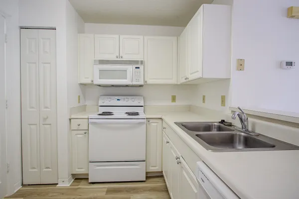 a kitchen with white cabinets and white appliances