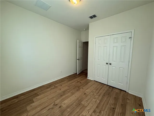 a view of an empty room with closet and a window