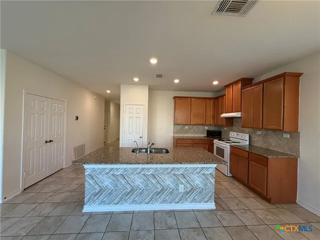 a kitchen with stainless steel appliances granite countertop a sink a stove a microwave a counter top and cabinets