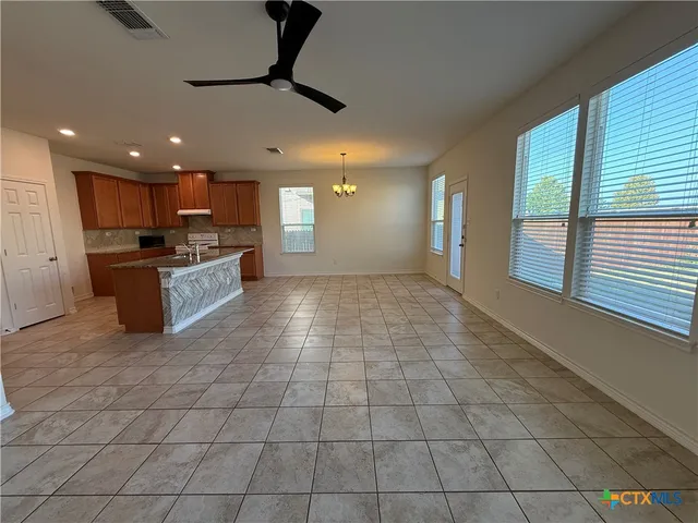 a view of a kitchen with kitchen island stainless steel appliances a stove a sink a counter top space cabinets and a window