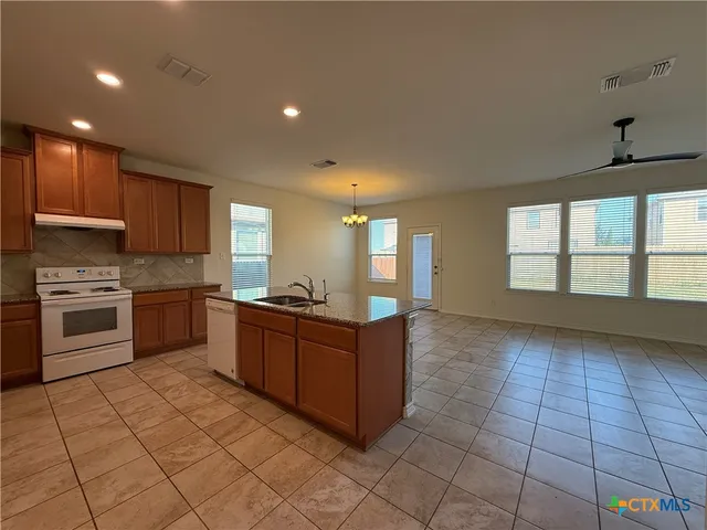a kitchen with stainless steel appliances granite countertop a stove a sink and a microwave