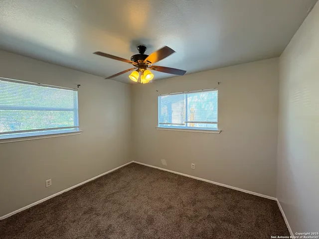 an empty room with a window and ceiling fan