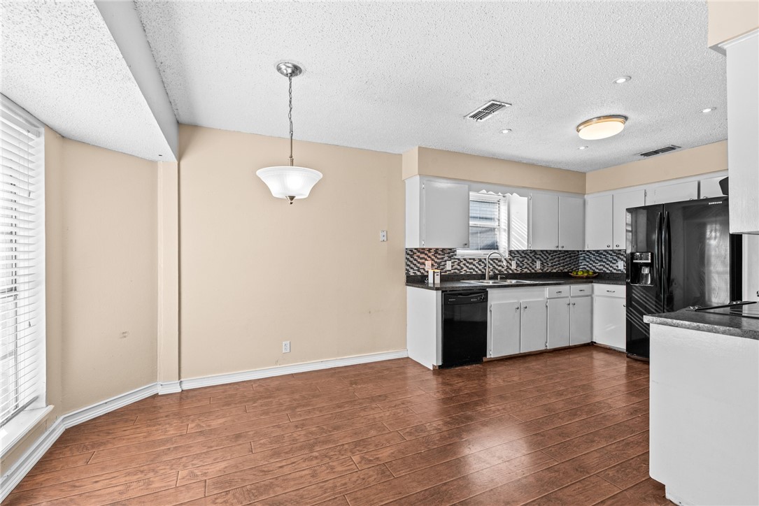1910 Cherokee Street Corpus Christi, TX 78409 - Photo 6 of 23 a kitchen with stainless steel appliances granite countertop a refrigerator a sink dishwasher a stove and white cabinets with wooden floor