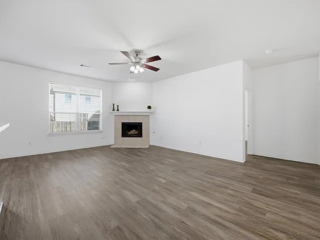 an empty room with wooden floor ceiling fan and windows