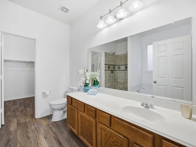 a spacious bathroom with a granite countertop sink a toilet and a large mirror