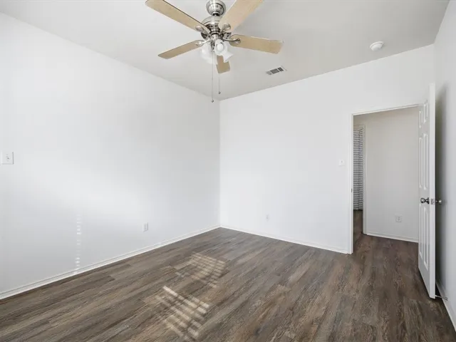 an empty room with wooden floor and fan
