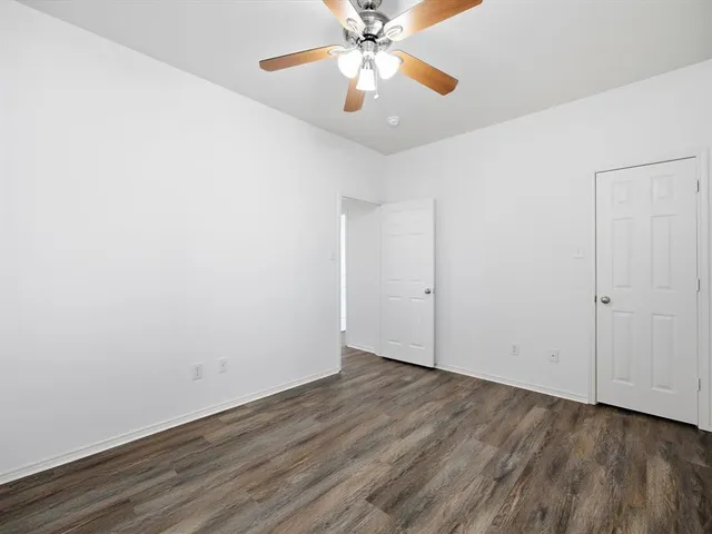 an empty room with wooden floor chandelier fan and closet area