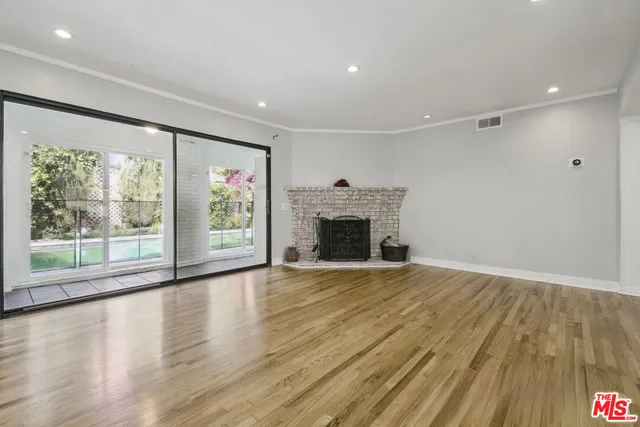a view of empty room with wooden floor and fireplace