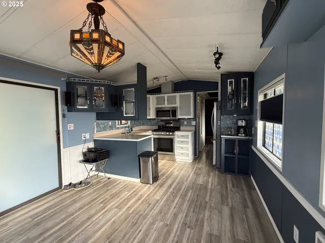 a kitchen with stainless steel appliances a refrigerator a stove a sink dishwasher and wooden cabinets with wooden floor