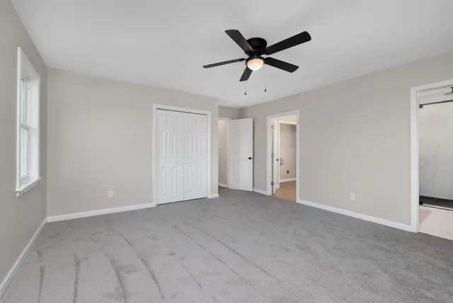 an empty room with a window and a ceiling fan