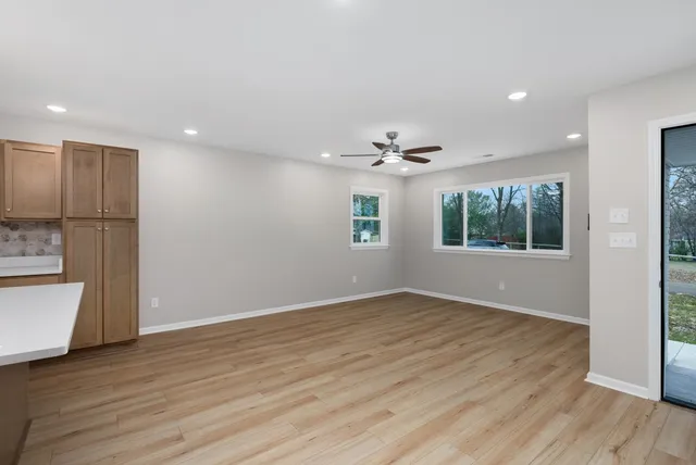 a view of an empty room with a window and wooden floor
