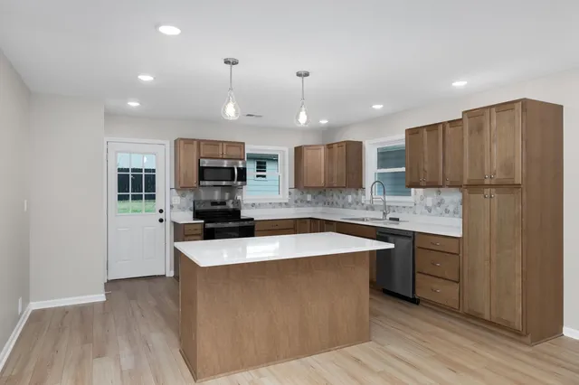 a large kitchen with stainless steel appliances kitchen island a large counter top and a stove top oven