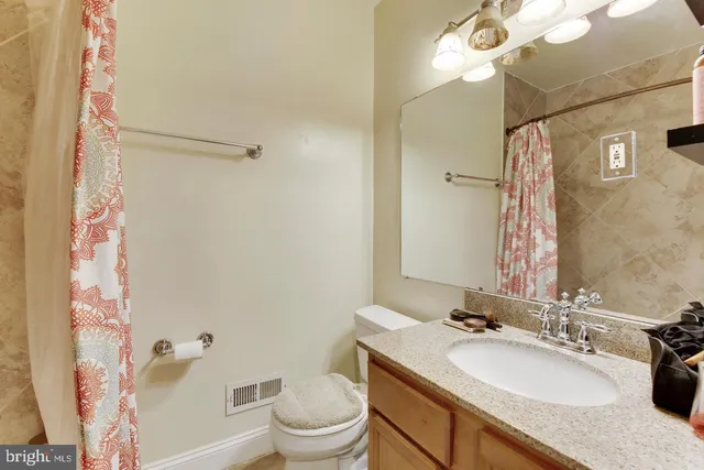 a bathroom with a granite countertop sink toilet a mirror a vanity and shower