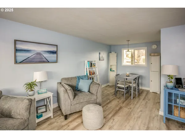 a living room with furniture and a dining table with kitchen appliances