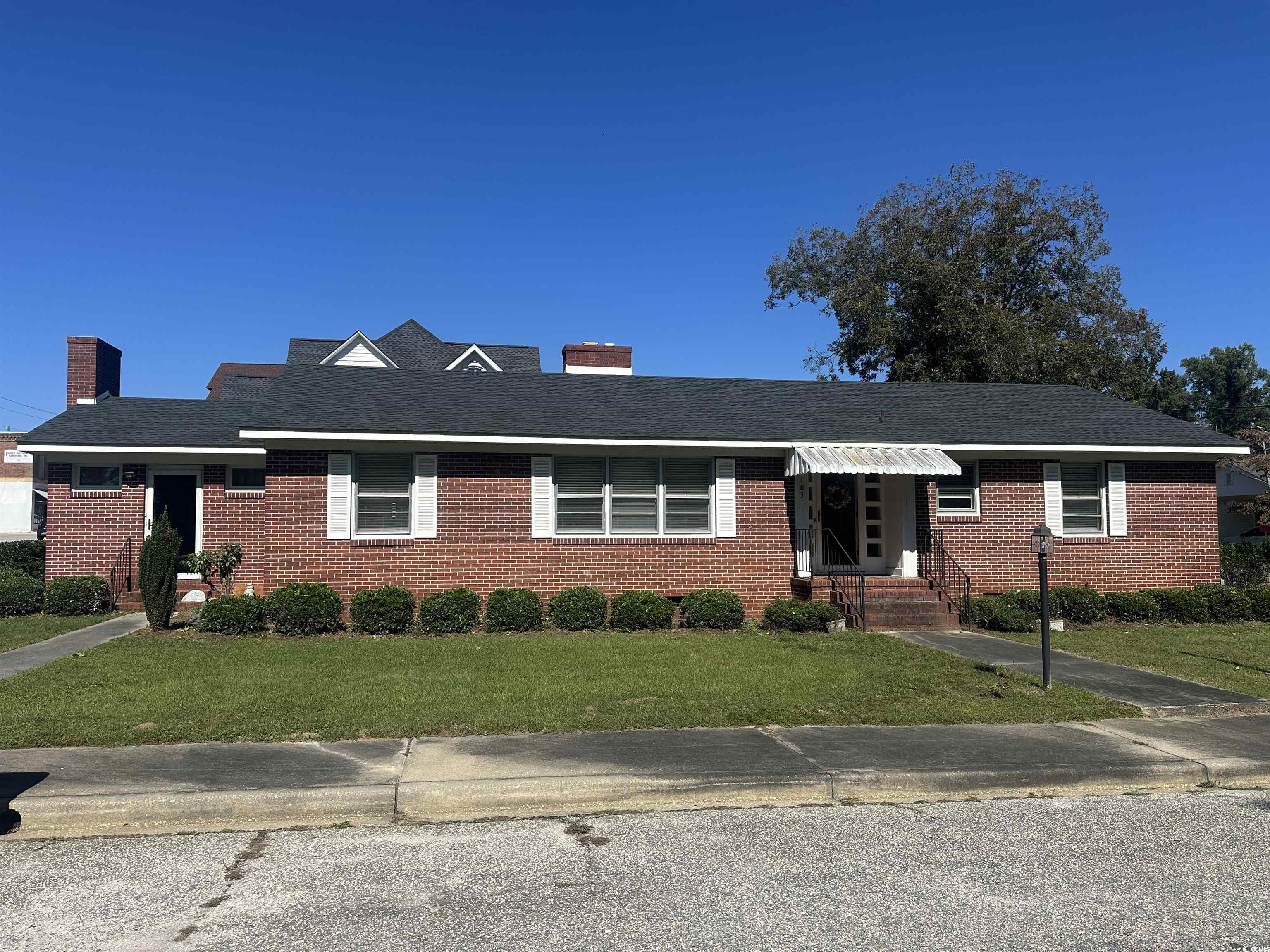 103 East 2nd Avenue Lake View, SC 29563 - Photo 1 of 16 Ranch-style home featuring a front yard, a chimney, brick siding, and a shingled roof