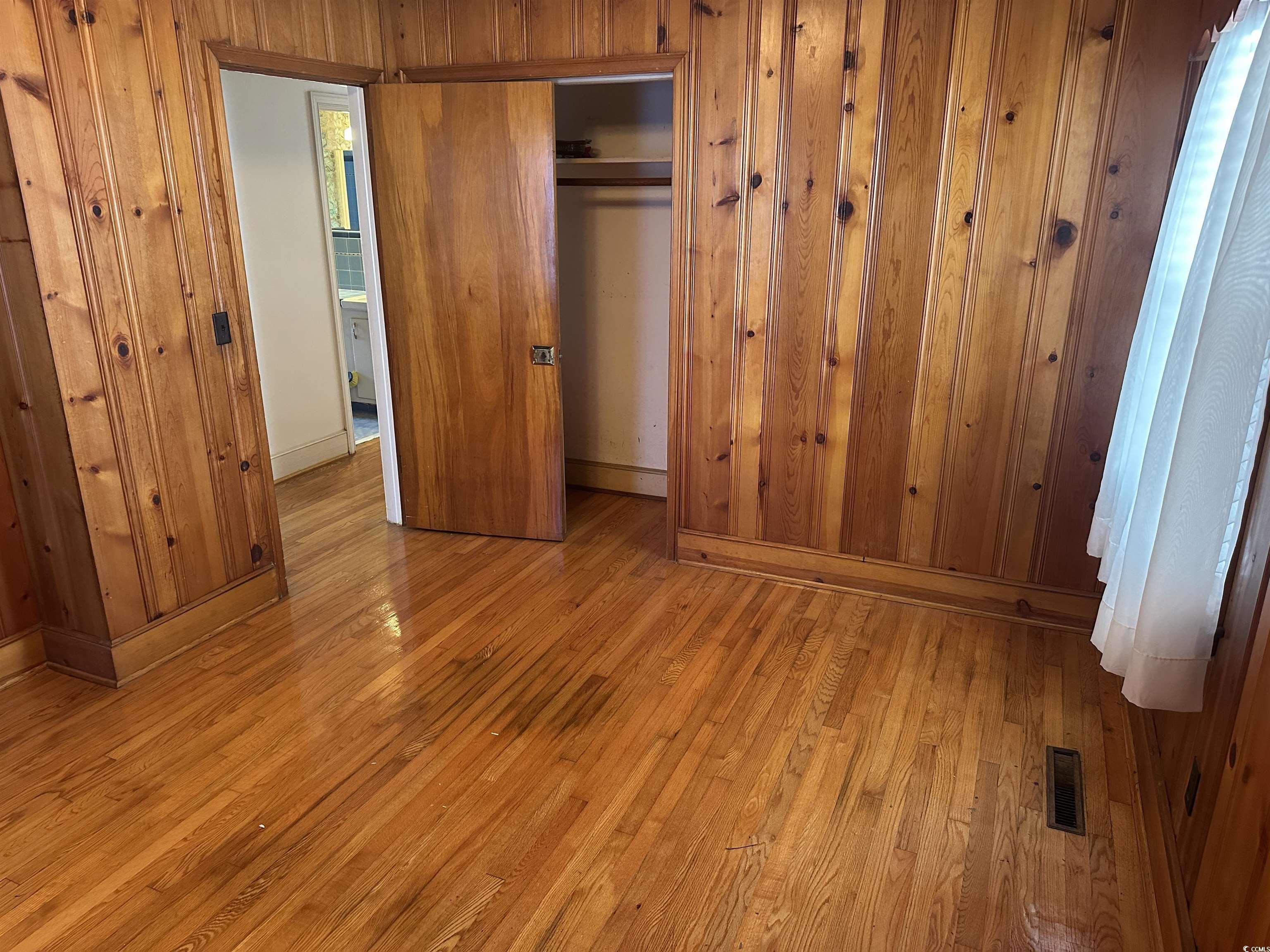 103 East 2nd Avenue Lake View, SC 29563 - Photo 11 of 16 Unfurnished bedroom with hardwood / wood-style flooring, a closet, and wooden walls